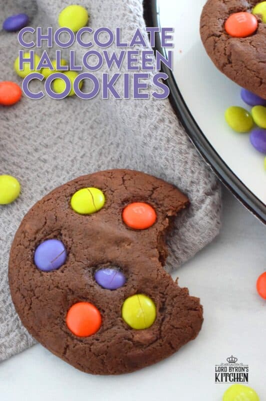 Chocolate Halloween Cookies have a slightly crispy exterior with a dense chocolaty center. Stuffed with white chocolate chips and topped with green, purple, and orange M&M candy, these cookies are both delicious and festive!  Your little trick-or-treaters are going to love these! #m&m #halloween #cookies #chocolate #trickortreat