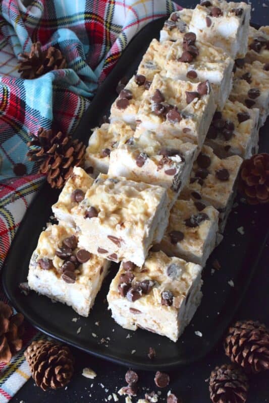 These no-bake treats are prepared with lots of white chocolate, creamy peanut butter, a few cups of rice cereal, and a good helping of marshmallows too. Holiday Avalanche Squares are absolutely delicious! The white chocolate is melted together with the peanut butter, and once cooled, the other ingredients are folded in to create these wonderfully high and cloudy-soft squares! #squares #bars #nobake #christmas #holiday #baking #cookies #chocolate
