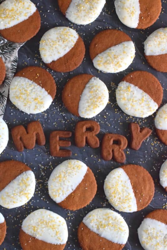 Thin and crispy Tuxedo Gingersnap Cookies are loaded with traditional Christmastime ingredients, like molasses, cinnamon, and ginger! Once cooled, half of each cookie is dipped into melted white chocolate and sprinkled with edible glitter. These cookies taste even better than they look; and I think they look amazing! #tuxedo #gingersnap #cookies #christmas #holiday #baking