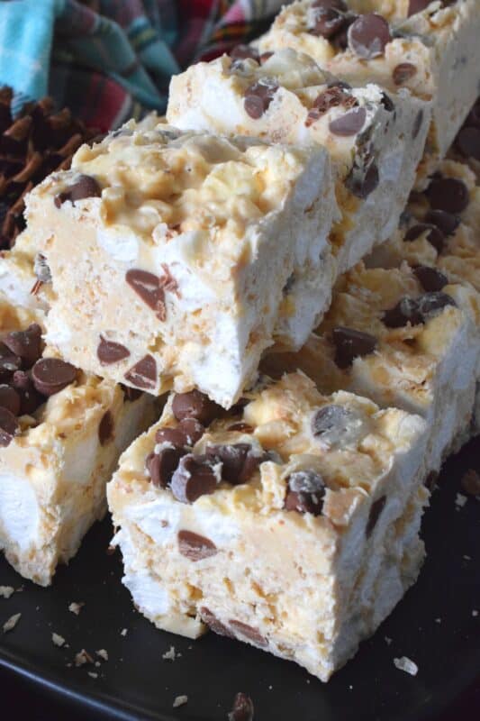 These no-bake treats are prepared with lots of white chocolate, creamy peanut butter, a few cups of rice cereal, and a good helping of marshmallows too. Holiday Avalanche Squares are absolutely delicious! The white chocolate is melted together with the peanut butter, and once cooled, the other ingredients are folded in to create these wonderfully high and cloudy-soft squares! #squares #bars #nobake #christmas #holiday #baking #cookies #chocolate
