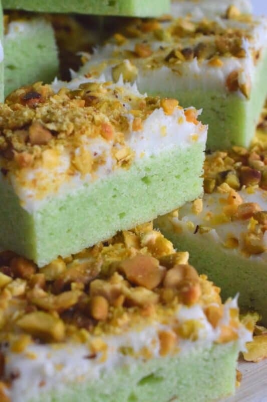 The uncomplicated and delicious sugar cookie gets a fresh, new flavour profile, and an upgrade in this Pistachio Sugar Cookie Squares recipe.  The classic sugar cookie base is pistachio flavoured and prepared with boxed pistachio pudding powder.  Topped with a layer of delicious buttercream frosting and sprinkled with roasted, salted chopped pistachios, this cookie is simply irresistible! #pistachio #sugarcookies #cookies #christmas #holiday #squares #baking