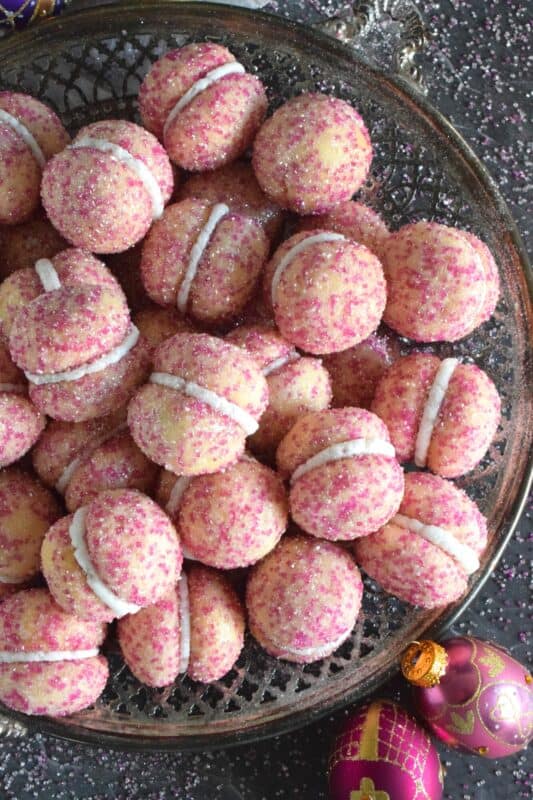 These beautiful, shimmering, Glittery Sugar Plum Cookies are the epitome of priceless luxury on a dollar store budget.The cookies are baked with a sparkling, sugary coating and sandwiched together with an easy, sweet frosting. One bite and you'll certainly have visions of these sugar plums dancing in your head on Christmas Eve night! #sugarplums #christmas #baking #cookies #glitter