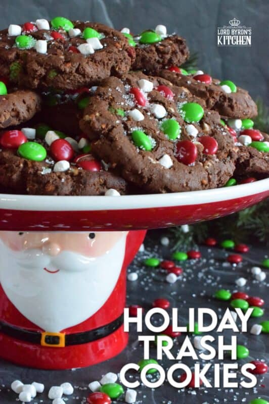 Holiday Trash Cookies are loaded with both milk and white chocolate chips, M&Ms, crushed pretzels, and marshmallow bits too! The cookie dough is prepared with brown sugar, which means these cookies are soft and moist on the inside, but they have a crisp exterior! Make a delightfully tasty gift by packaging these festive cookies up in boxes and tying them with a bright festive ribbon! #mandm #christmas #santa #cookies #trash