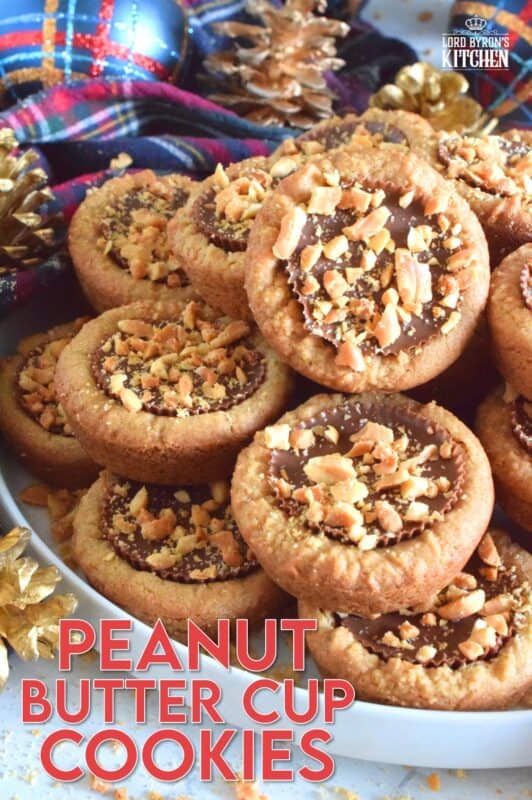 Thumbprint-style cookies are very popular at Christmastime, so why not over-stuff them with a full-sized Peanut Butter Cup? These cookies are so easy to make and are baked in muffin tins! Push in the peanut butter cup and top with chopped peanuts for more texture and flavour! #peanutbutter #reeses #cookies #thumbprint