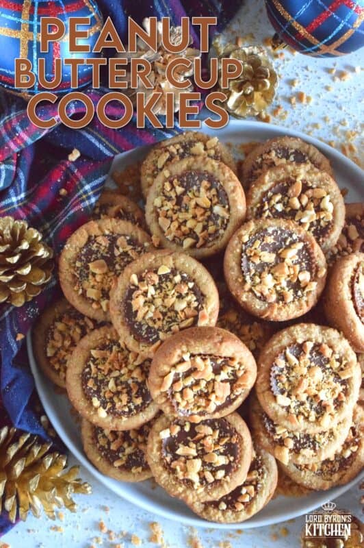 Thumbprint-style cookies are very popular at Christmastime, so why not over-stuff them with a full-sized Peanut Butter Cup? These cookies are so easy to make and are baked in muffin tins! Push in the peanut butter cup and top with chopped peanuts for more texture and flavour! #peanutbutter #reeses #cookies #thumbprint