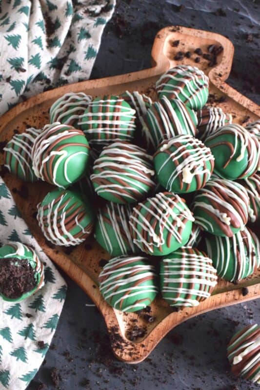 Otherwise known as truffles, these Mint Oreo Balls are prepared with crushed mint-flavoured Oreos and cream cheese. They are dipped in melted green candy melts and drizzled with milk and white melted chocolate. They're bright, beautiful, festive, and delicious! #oreo #truffles #balls #nobake #christmas