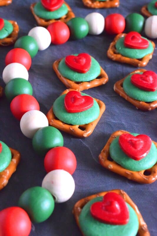 Oftentimes, these types of snacks are prepared with a Hershey's Kiss or a Rolo chocolate candy. But, Grinch Pretzel Treats needed something green and red, so the obvious choice was to top the pretzels with a green candy melt and a big shiny red heart. Aren't they cute!? #grinch #pretzel #treats