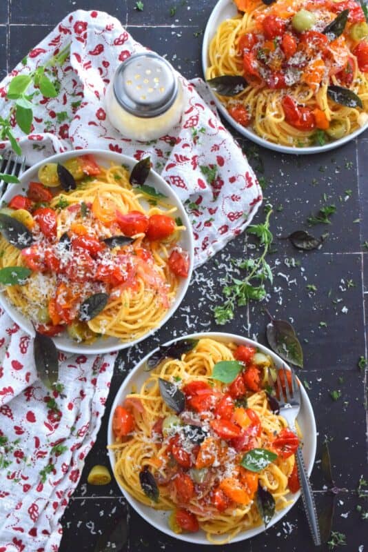 Herb and Garlic Tomato Spaghetti is one of those quick and easy recipes that taste wonderfully delicious! This simple pasta is prepared using fresh herbs like thyme, oregano, and chives.  Cherry tomatoes are blistered with red onions in olive oil to create a sauce. Tossed with perfectly cooked pasta, this dish is a family-friendly meal, but impressive enough for any dinner party! #herbs #pasta #tomatoes #spaghetti