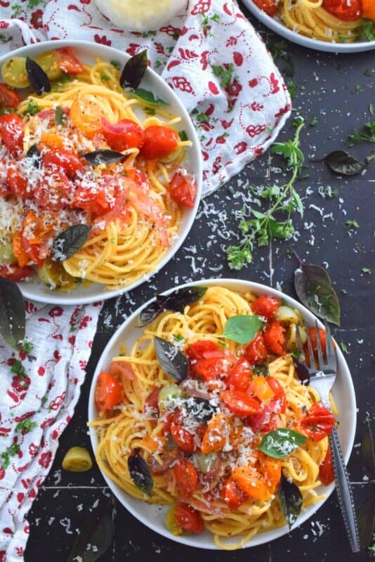 Herb and Garlic Tomato Spaghetti is one of those quick and easy recipes that taste wonderfully delicious! This simple pasta is prepared using fresh herbs like thyme, oregano, and chives.  Cherry tomatoes are blistered with red onions in olive oil to create a sauce. Tossed with perfectly cooked pasta, this dish is a family-friendly meal, but impressive enough for any dinner party! #herbs #pasta #tomatoes #spaghetti