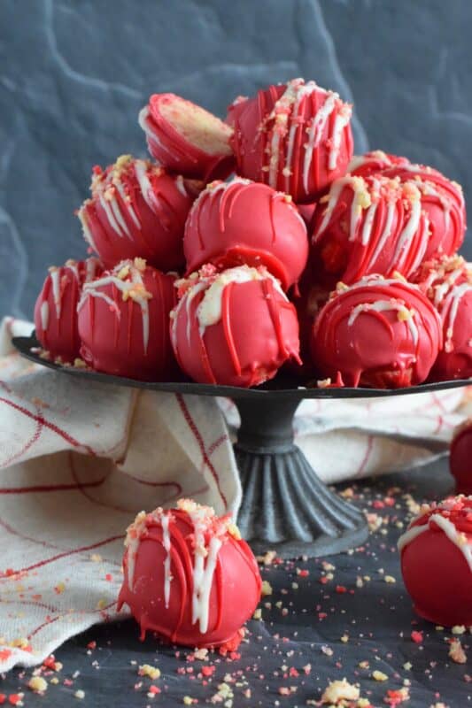 Prepared with crushed vanilla-flavoured Golden Oreos, cream cheese, and homemade strawberry shortcake crumbs, these Strawberry Shortcake Truffles are dipped in melted red candy melts and drizzled with white melted chocolate. They’re beautifully bold and bright, and delicious too! #truffles #valentines #nobake #pink #candy