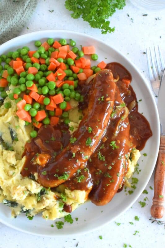 The ultimate comfort food is mashed potatoes and gravy. Serving pan-fried bangers with the two is a no-brainer! This hearty, family-friendly meal is easy to prepare and quite delicious. Bangers and Mash with Homemade Onion Gravy might be considered peasant food, but I'd serve this to the fanciest of folks without any hesitation! #bangers #mash #irish #stpatricksday