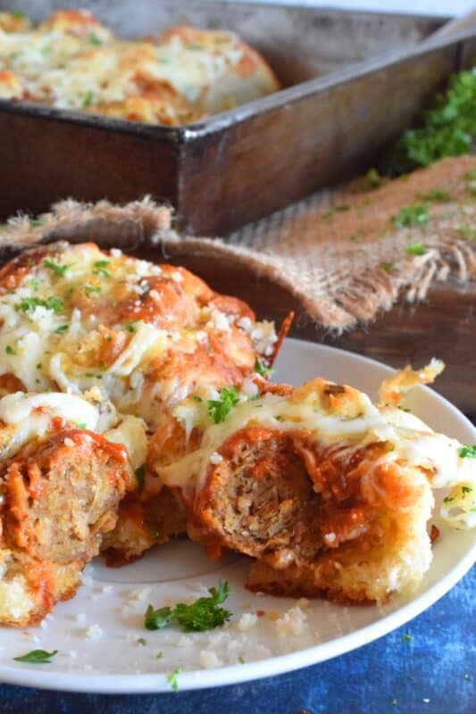 Garlic Bread Meatball Bombs are hollowed out dinner rolls which have been liberally smeared with homemade garlic butter. Each roll is stuffed with a meatball and sauce, then topped with cheese. Baked to a bubbling, gooey perfection, these bombs are the bomb! #meatballs #sliders #dinnerrollrecipes #bombs #meatballrecipes #familyrecipes #garlicbread