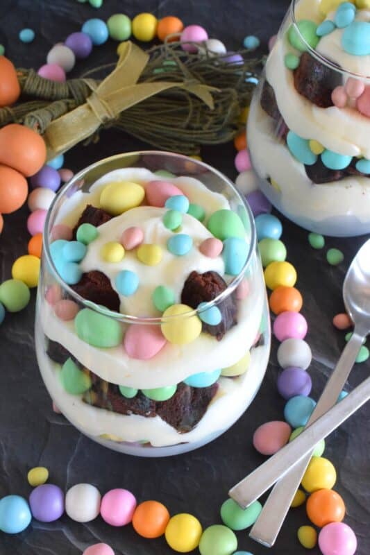 Crumbled brownies are layered with chocolate mini eggs and a homemade cream cheese filling in this Easter Cheesecake Parfait recipe. Easily prepare everything a few days ahead of time and assemble the parfaits when ready to serve. Make extra because these are deliciously addictive! #easter #dessert #parfait #brownie #minieggs