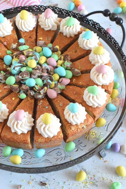 Prepared with crushed chocolate mini eggs and topped with a dollop of buttercream frosting, this Easter Mini Egg Tea Cake looks quite delicious and inviting! Keep the decorating simple with a pile of mini eggs right in the center and let the cake speak for itself! A delightful treat, this cake is a beautiful Easter dessert! #minieggs #easter #cadbury #cake #teacake