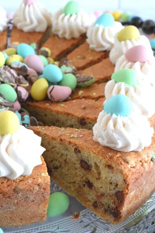 Prepared with crushed chocolate mini eggs and topped with a dollop of buttercream frosting, this Easter Mini Egg Tea Cake looks quite delicious and inviting! Keep the decorating simple with a pile of mini eggs right in the center and let the cake speak for itself! A delightful treat, this cake is a beautiful Easter dessert! #minieggs #easter #cadbury #cake #teacake