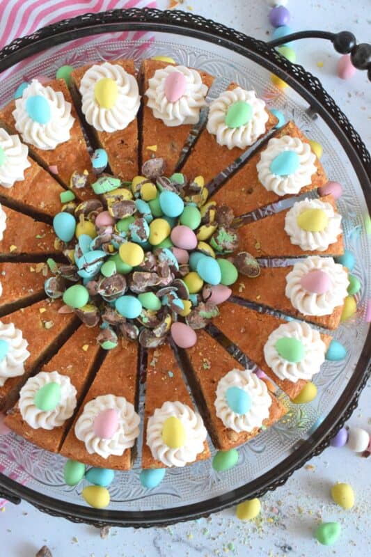 Prepared with crushed chocolate mini eggs and topped with a dollop of buttercream frosting, this Easter Mini Egg Tea Cake looks quite delicious and inviting! Keep the decorating simple with a pile of mini eggs right in the center and let the cake speak for itself! A delightful treat, this cake is a beautiful Easter dessert! #minieggs #easter #cadbury #cake #teacake