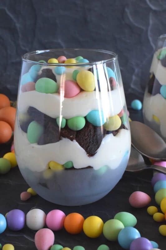 Crumbled brownies are layered with chocolate mini eggs and a homemade cream cheese filling in this Easter Cheesecake Parfait recipe. Easily prepare everything a few days ahead of time and assemble the parfaits when ready to serve. Make extra because these are deliciously addictive! #easter #dessert #parfait #brownie #minieggs