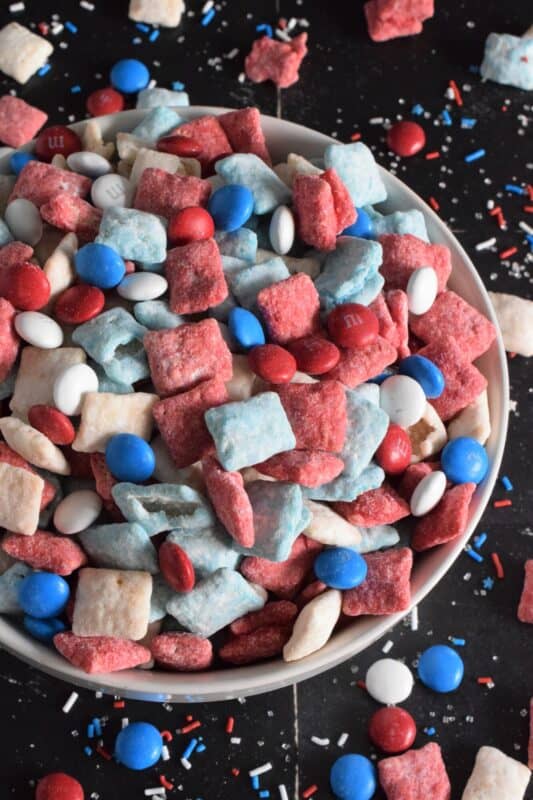 Assemble these 4th of July Muddy Buddies and serve them to your guests this Independence Day long weekend! Loaded with sugary treats, this snack mix will disappear quite quickly! Friends can help themselves to a tasty treat at your party, or scoop some into cellophane bags and tie them up with a festive ribbon as a take-home treat! #muddybuddies #4thofjuly #redwhiteandblue