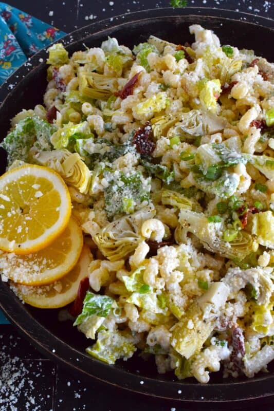 Prepared with pasta, lettuce, canned artichokes, chopped sun-dried tomatoes, onions, and parmesan, this salad can be a delicious side or a complete meal! The hot and hazy days of summer are just weeks away, so save this recipe now for your backyard barbecues and those family picnics! #sundried #tomato #pasta #salad #artichoke