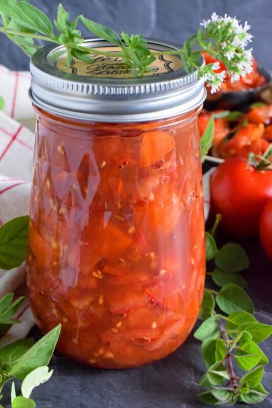 Summer fresh tomatoes are packed into jars and canned with fresh garlic and red onions. Well-seasoned and preserved Canned Tomato Bruschetta can be easily and quickly assembled at any time! Pile onto grilled bread or toss with cooked pasta for a delicious meal! This is a great way to preserve your homegrown tomatoes! #bruschetta #canned #tomatoes #preserved
