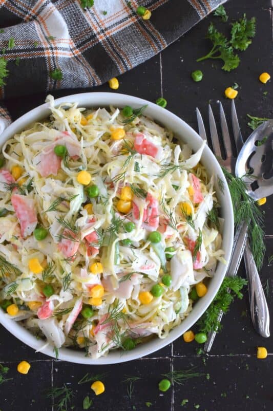 Chunks of crab and lobster are tossed with lots of fresh vegetables, like cabbage, cucumber, corn, peas, and green onions in a homemade creamy, tangy, and savoury dressing. Consider your budget and use real seafood or imitation crab and lobster to make this absolutely refreshing Seafood Coleslaw Salad! #seafood #salad #coleslaw #imitation #crab #lobster