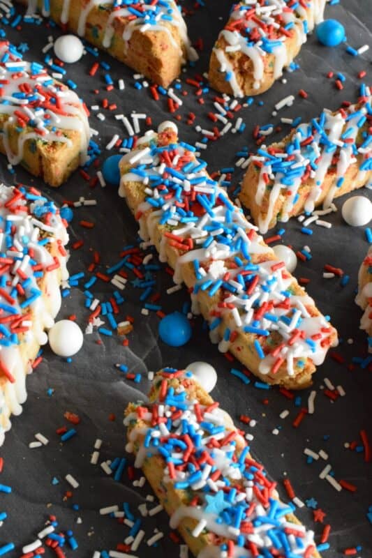 These crisp Red White and Blue Biscotti are so easy to make and they're so brightly coloured and festive, no one could resist!  Loaded with red, white, and blue sprinkles, and topped with a sweet sugary glaze, these are great for your 4th of July party, and even better when sitting on your back porch with a hot coffee on a lazy Saturday morning! #biscotti #redwhiteandblue #4thofjuly