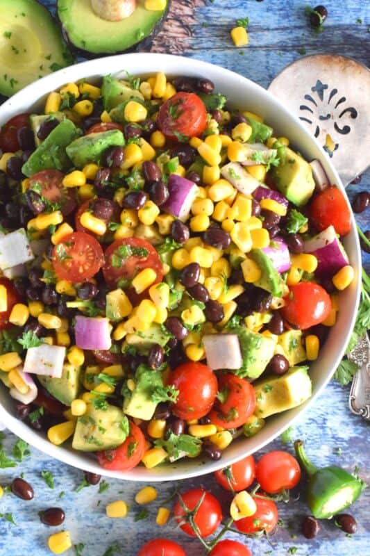 Some salads are meant to be served as a side dish and some salads, like this Avocado Corn and Bean Salad, are hearty enough to be a main. Filled with heart-healthy vegetables, and tossed in an oil and lime juice dressing, this salad is refreshingly perfect for summer! #avocado #blackbean #salad #summersalad