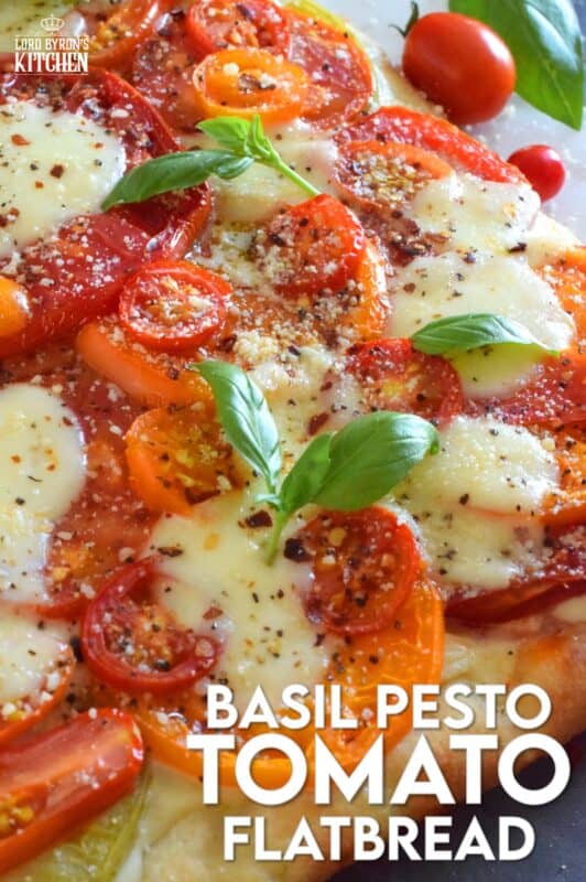 Freshly sliced tomatoes and cheese are piled onto a quick and easy homemade flatbread with the best double parmesan basil pesto sauce. Baked to perfection and topped with fresh basil leaves and ground black pepper, this is a very scrumptiously delicious recipe! #tomatoes #flatbread #heirloom #summerfresh