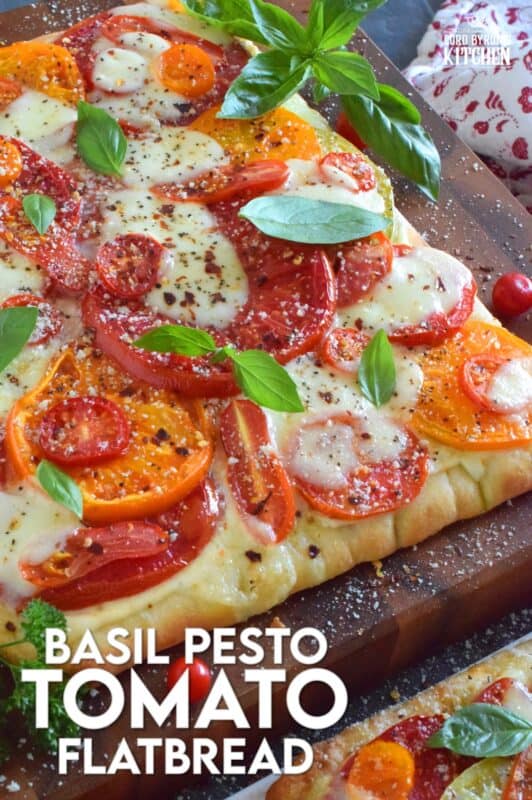 Freshly sliced tomatoes and cheese are piled onto a quick and easy homemade flatbread with the best double parmesan basil pesto sauce. Baked to perfection and topped with fresh basil leaves and ground black pepper, this is a very scrumptiously delicious recipe! #tomatoes #flatbread #heirloom #summerfresh