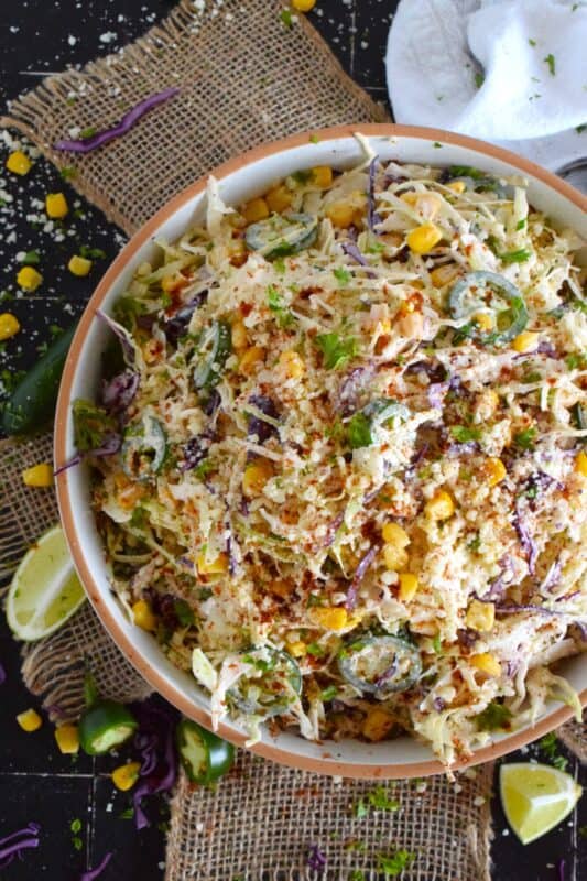 Crisp red and green cabbage, sweet corn, spicy jalapenos, fresh green onions, and salty cotija cheese all meet in the middle to create this most delicious Mexican Street Corn Coleslaw. With its creamy, zingy, and tart dressing, this coleslaw will most definitely please the toughest critic! #mexican #streetcorn #coleslaw #salad