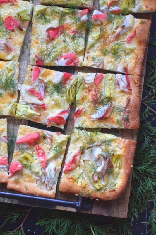 Cheesy, garlicky, and spicy are three words one could use to describe this Artichoke and Crab Flatbread.  Easy to prepare, but authentically delicious, this appetizer will be talked about long after the holidays are over, which is why this recipe makes two! #appetizer #seafood #crab #holiday #christmas #flatbread
