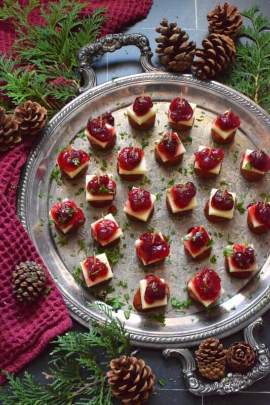 Oven-roasted smoked sausage is topped with a slice of aged cheddar cheese and dressed with cranberries. The big-bite combination of salty sausage, and creamy cheese, with sweet and bitter cranberries, is delightful! #cranberry #sausage #appetizer #holiday #christmas