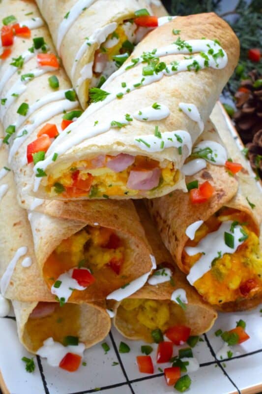 Eggs, bell peppers, onions, shredded cheese, and chopped cooked ham are the ingredients that make up the popular Western Omelette breakfast.  For these taquitos, the omelette was fully prepared, rolled in a flour tortilla and baked until golden brown.  These make a delicious breakfast that can easily be prepared in advance and frozen. #western #omelette #taquitos #breakfast