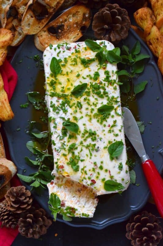 This Holiday Cheese Log is packed with a tonne of flavourful add-ins, such as chili flakes, roasted red peppers, sun-dried tomatoes, and fresh chives. Seasoned with garlic, onion, basil, oregano, and more, this holiday appetizer is a tremendously delicious party favourite! #cheeselog #appetizer #holiday #christmas