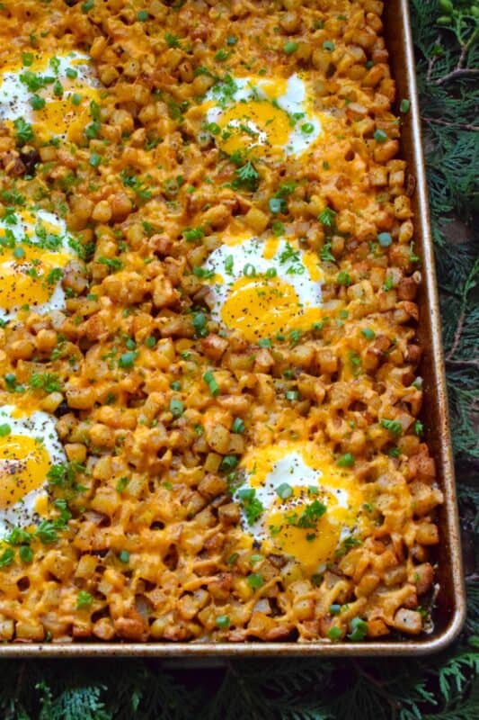 A one-pan breakfast recipe to feed a hungry and excited family is exactly what this Sheet Pan Potato and Egg Breakfast is all about! Frozen shredded hash browns are seasoned and baked in butter while eggs are cracked right on top with lots of shredded cheese. Who wouldn’t want this for breakfast on Christmas morning? #breakfast #brunch #sheetpan #hashbrowns #eggs