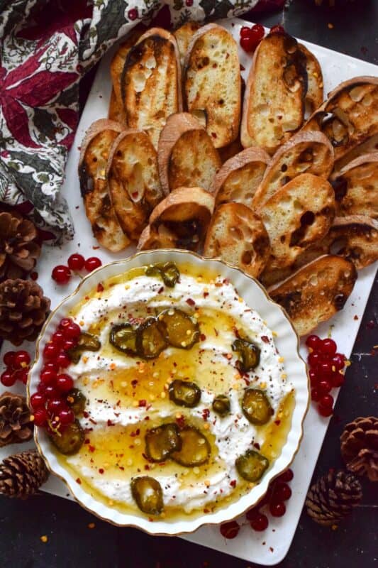 When you whip ricotta with garlic, onion, oregano, and sour cream, not only is the flavour incredible, but the texture is silky smooth. Topped with homemade Jalapeno Honey, this dip is cool and spicy at the same time. Serve with your favourite crackers and bread. #ricotta #appetizer #spread #dip #cheese #honey #jalapeno