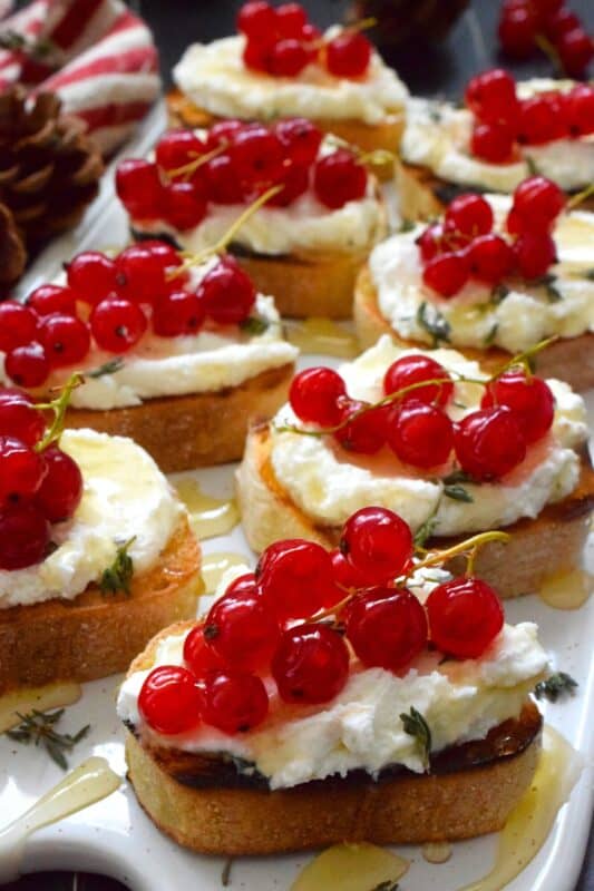 Toast or grill thinly sliced bread and top it with whipped goat cheese. Drizzle over your favourite honey and garnish with fresh thyme leaves and berries. Honeyed Cheese Bread is sweet and salty and is completely irresistible. The creaminess of the cheese and honey is a great match for the chewiness of the toasted baguette. #honey #bread #appetizer #christmas #holiday