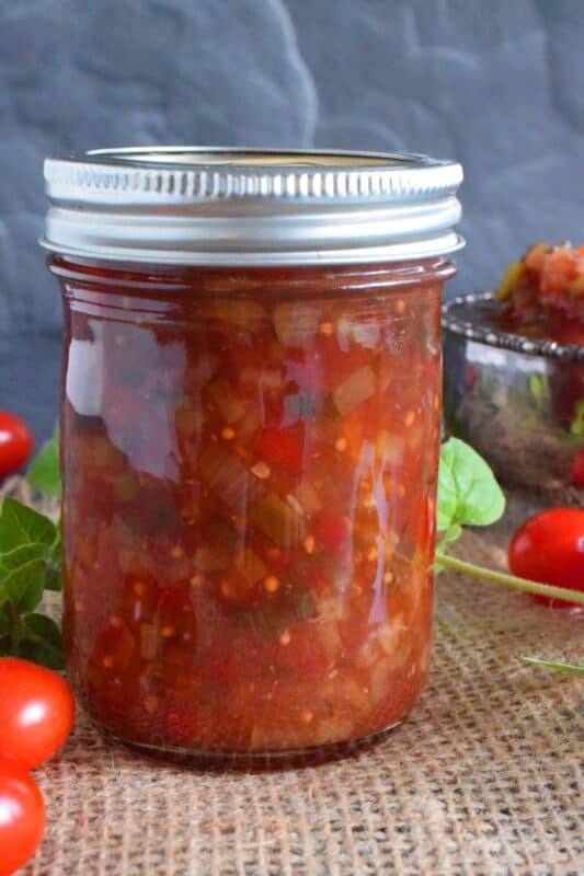 Spoon this Canned Tomato Relish onto hamburgers, hotdogs, sausages, and sandwiches too. Prepared with cucumbers, bell peppers, zucchini, onion, and tomatoes, this relish is the best way to preserve all of that homegrown late-summer harvest! #hamburger #tomato #relish #canning #preserves #tomatoes