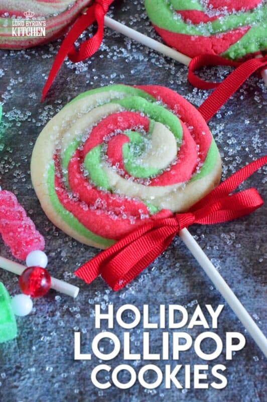Add colour and pizzazz to your holiday cookie platter with these Holiday Lollipop Cookies! Spiralled and rolled cookie dough is topped with sparkling sugar and baked with a stick. These are sure to produce lots of smiles and crown you the winner of holiday baking! #lollipop #cookies #christmas