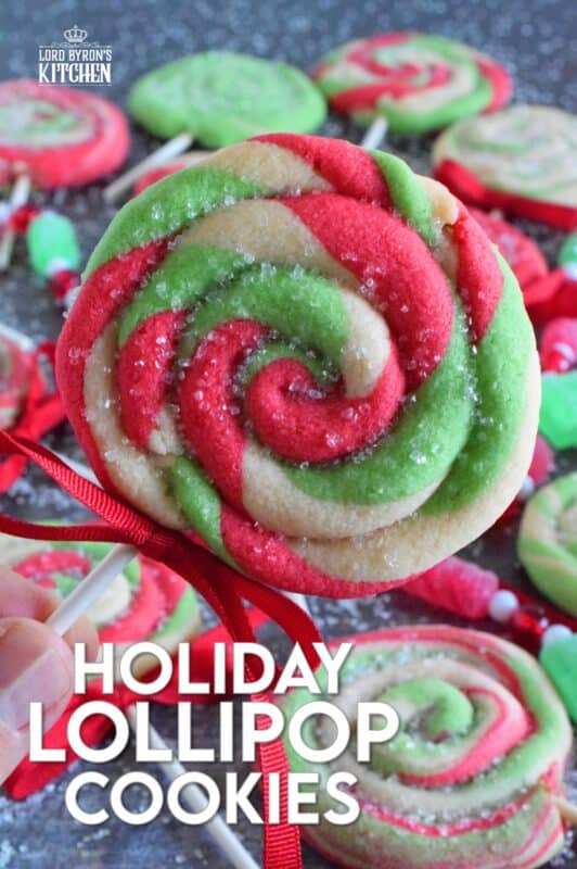 Add colour and pizzazz to your holiday cookie platter with these Holiday Lollipop Cookies! Spiralled and rolled cookie dough is topped with sparkling sugar and baked with a stick. These are sure to produce lots of smiles and crown you the winner of holiday baking! #lollipop #cookies #christmas