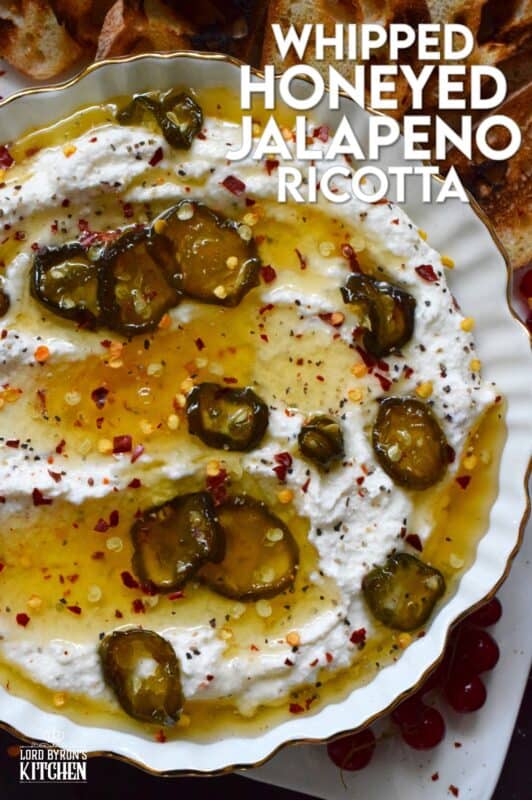 When you whip ricotta with garlic, onion, oregano, and sour cream, not only is the flavour incredible, but the texture is silky smooth. Topped with homemade Jalapeno Honey, this dip is cool and spicy at the same time. Serve with your favourite crackers and bread. #ricotta #appetizer #spread #dip #cheese #honey #jalapeno