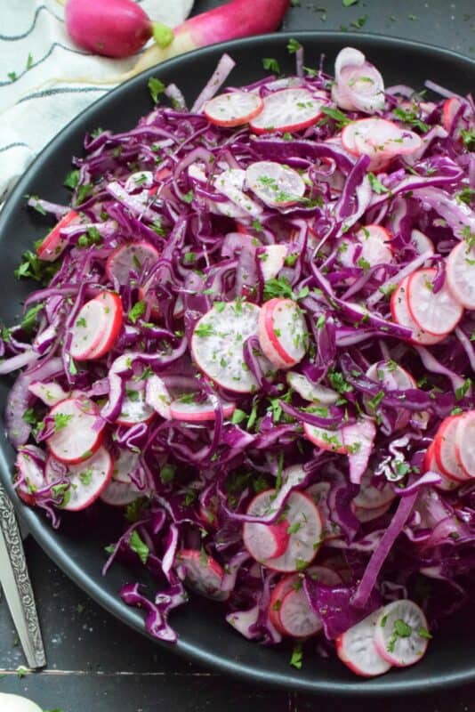 Fresh, crunchy red cabbage and peppery radish is paired with red onions to make this beautifully pink and purple Cabbage and Radish Coleslaw. Tossed with a homemade oil and vinegar dressing, this coleslaw is the epitome of fresh is best, and simple is better. #coleslaw #radish #cabbage #pinkandpurple