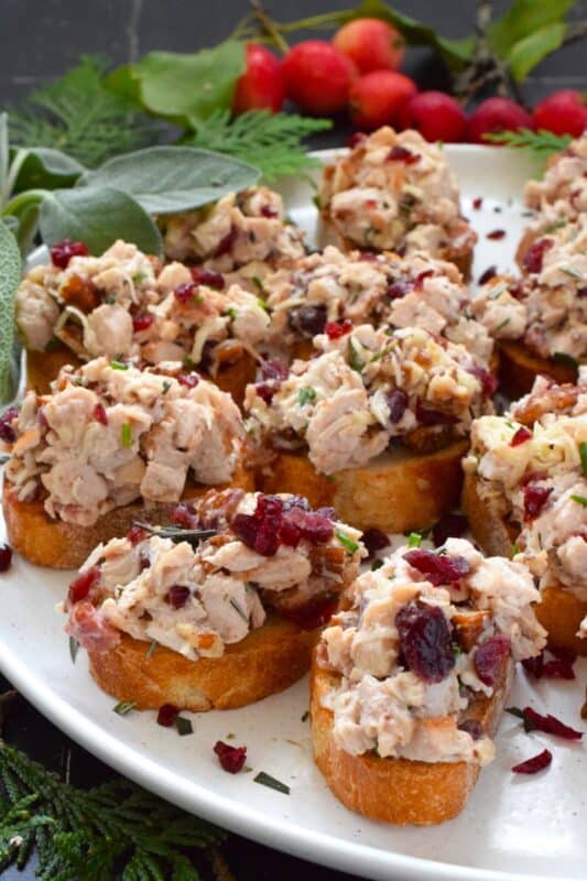 Chopped turkey breast meat is combined with bacon, cheese, and cranberries and piled onto lightly toasted or grilled bread. These crostini are savoury and sweet and have the makings of a great Christmas dinner in appetizer form. Alternatively, serve the turkey salad with crackers as a dip! #turkey #cranberry #crostini #appetizer #bacon