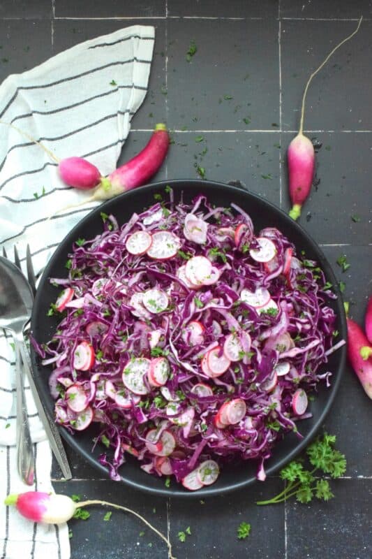 Fresh, crunchy red cabbage and peppery radish is paired with red onions to make this beautifully pink and purple Cabbage and Radish Coleslaw. Tossed with a homemade oil and vinegar dressing, this coleslaw is the epitome of fresh is best, and simple is better. #coleslaw #radish #cabbage #pinkandpurple