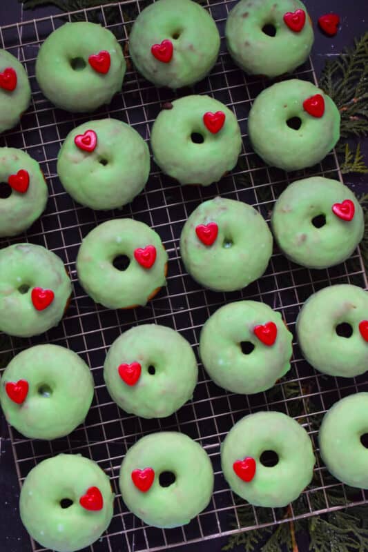 Grinch-themed confections are very popular at Christmastime, especially with kids! But even the adults will love these Grinch Christmas Donuts! Prepared with a baked basic donut recipe, these are dipped in green icing and despite the fact that the Grinch’s heart was three sizes too small, I’ve used the biggest red candy heart I could find! #ginch #donuts