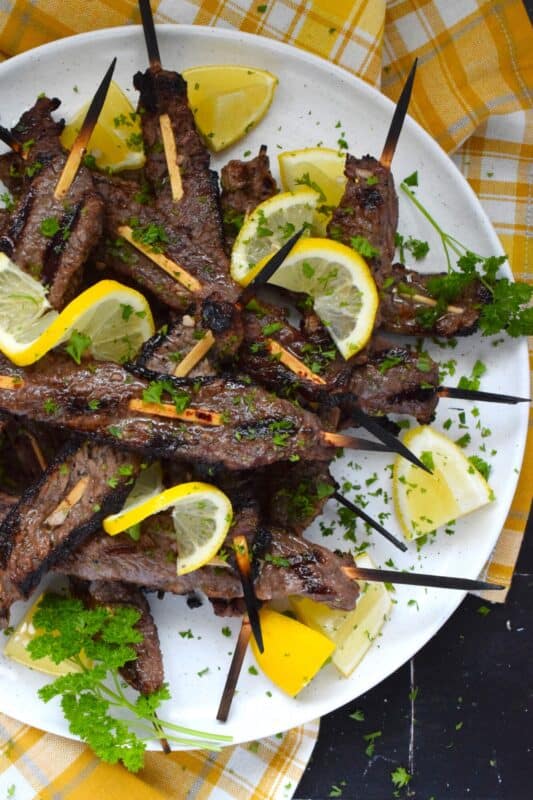 Thin slices of beef are marinated with fresh lemon juice, chopped garlic, and seasonings before being skewered and grilled to perfection!  Be sure to serve this Lemon Garlic Steak with lots of fresh lemons for extra zip and zing! #steak #grilled #garlic #lemon