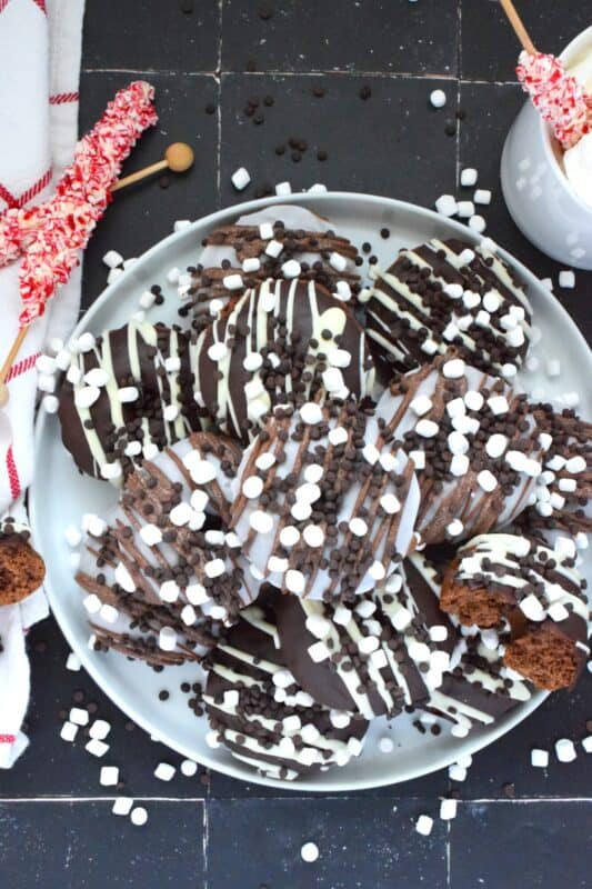 Good cocoa is the secret to a decadent hot chocolate; the same can be said for these Hot Chocolate Donuts.  Marshmallows are baked into the chocolate donut and sprinkled on top of the white glaze and the chocolate drizzle.  These baked donuts are for the ultimate chocolate lover! #hotchocolate #donuts #marshmallows