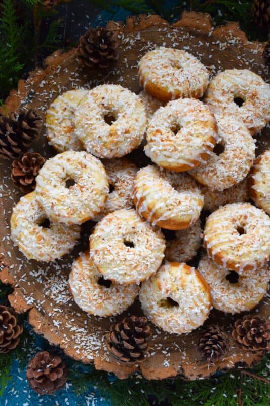 In our home, Christmas would not be Christmas without a confection prepared with coconut and these Toasted Coconut Donuts hit the mark! These are baked and not fried so they are super light! Imagine an old-fashioned glazed donut but with the addition of nutty, crispy toasted coconut - yum! #toasted #coconut #donuts