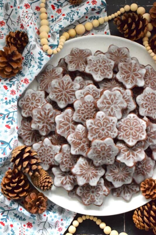 These thin and crispy chocolate cookies are a perfect holiday treat! Cocoa Snowflake Crisps are made with good cocoa and salted butter which help to make them super chocolatey and buttery with a snap-crisp texture. Top them with a thin sugary glaze to make them extra tasty and super festive too! #cocoa #chocolate #snowflake #cookies