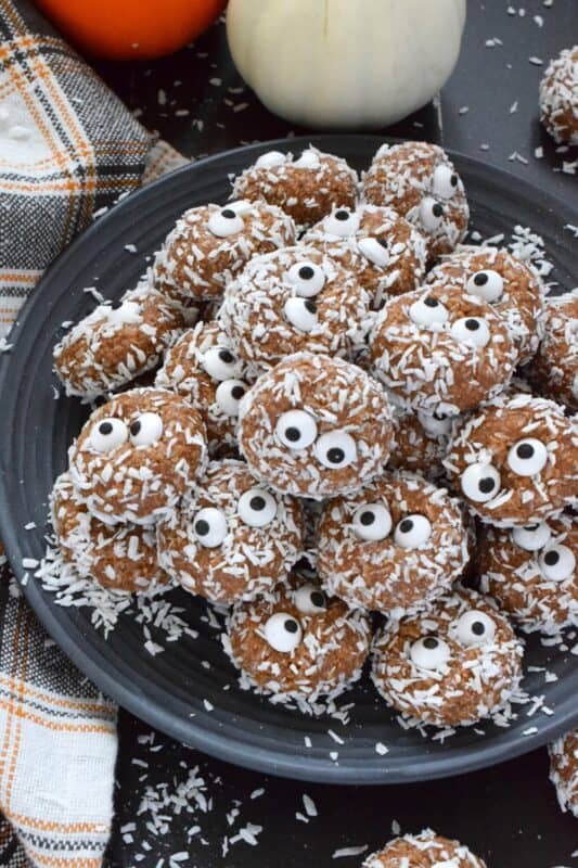 Prepared with melted marshmallows, cocoa powder, sweetened condensed milk, and graham cracker crumbs, No Bake Monster Cookies are sure to give you autumn smores vibes. The addition of the googly candy eyes in the center of each cookie helps make these cookies feel and look perfectly ready for Halloween! #halloween #monster #nobake #cookies #balls